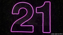 Neon pink number "21" sign illuminated against a dark background.