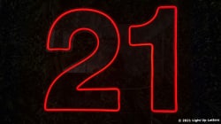 Red neon number "21" on a dark background.
