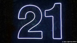 Neon light display of the number 21 against a dark background.